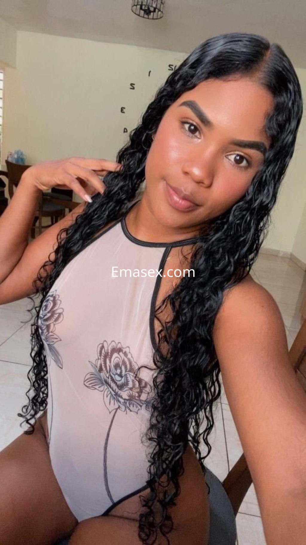 Puta en Córdoba posa con un body transparente con flores, luciendo su cabello largo y rizado.