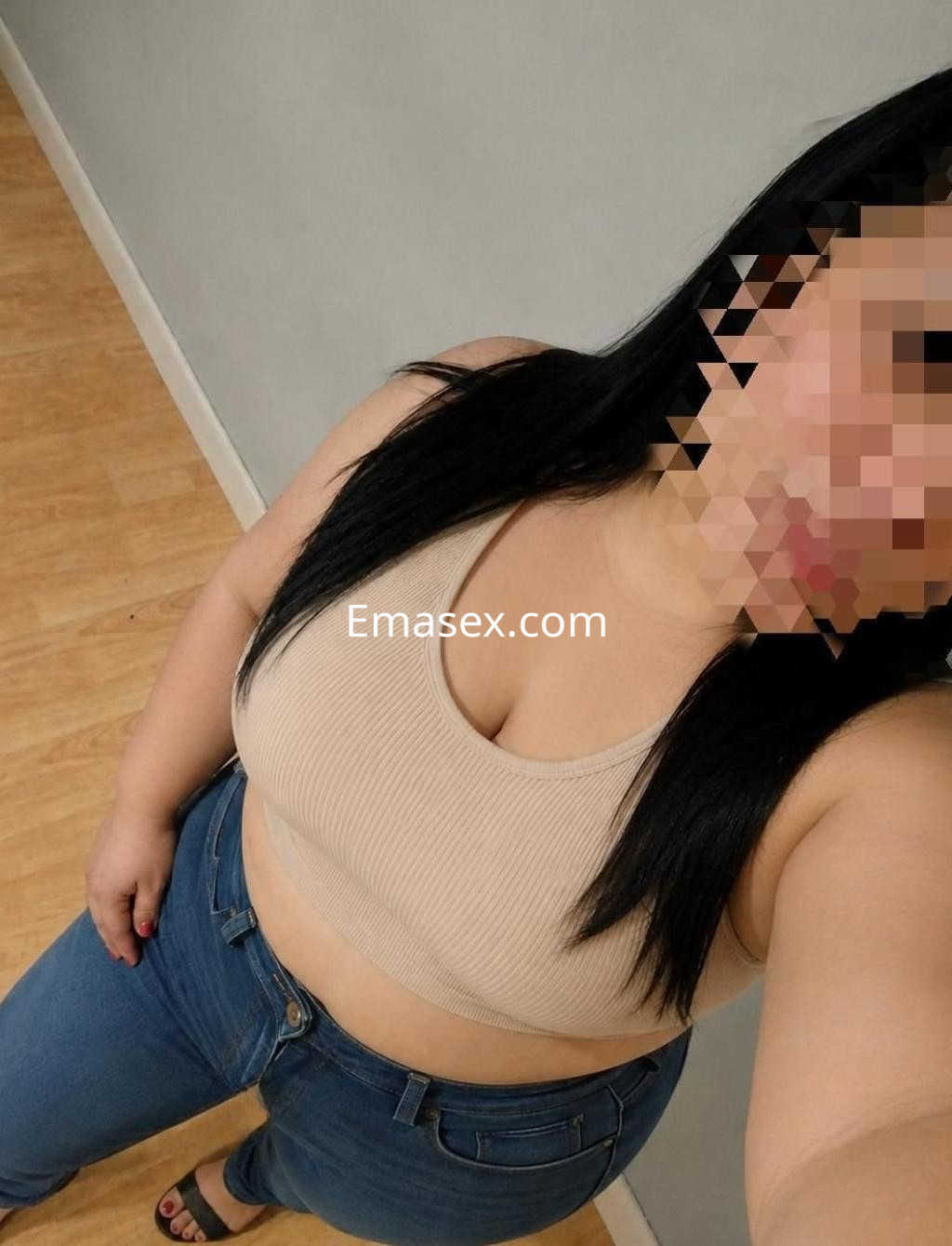 Escort en Oviedo con cabello largo y lacio, viste top claro y jeans ajustados, posando con confianza.