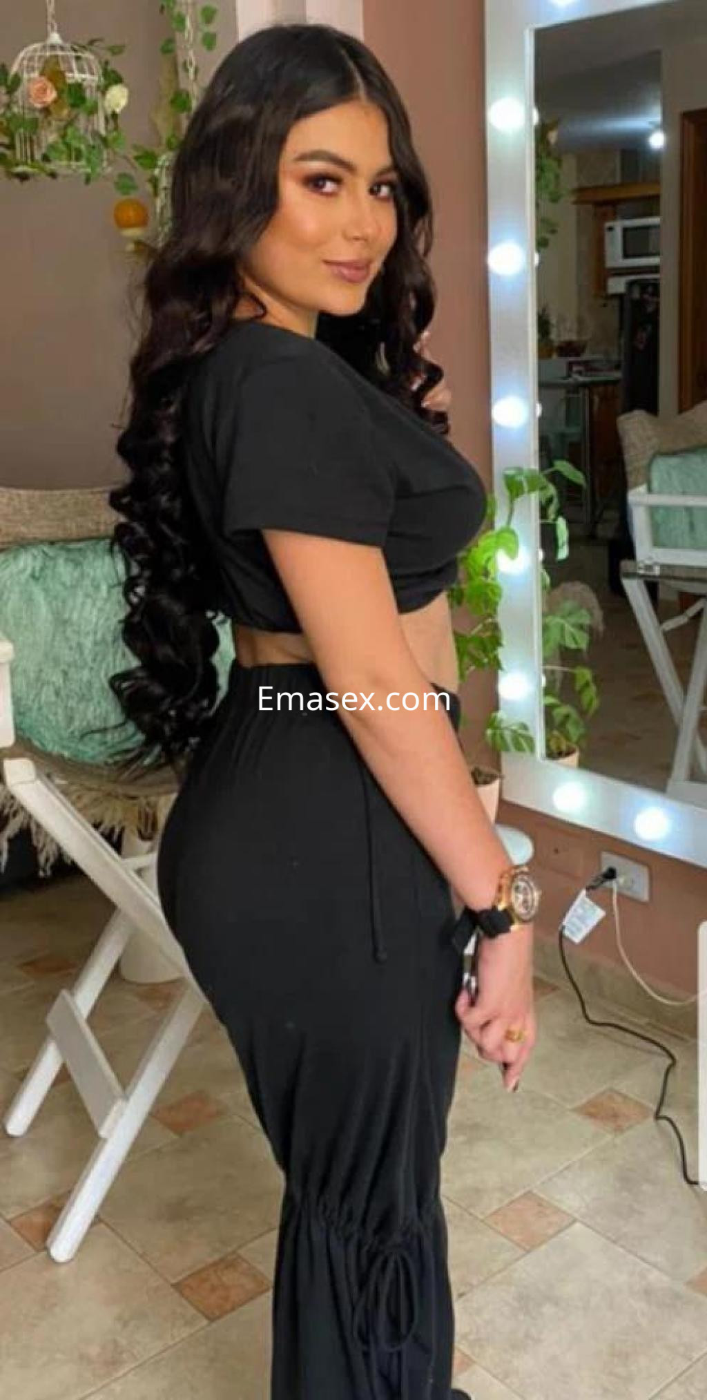 Escort en Palma de Mallorca con cabello largo y oscuro, vistiendo un conjunto negro ajustado en un ambiente acogedor.