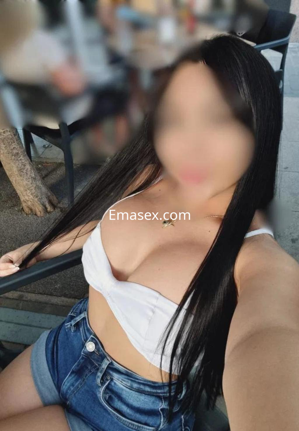 Puta con cabello largo y lacio, viste un top blanco y shorts de mezclilla, en un entorno al aire libre en Barcelona.