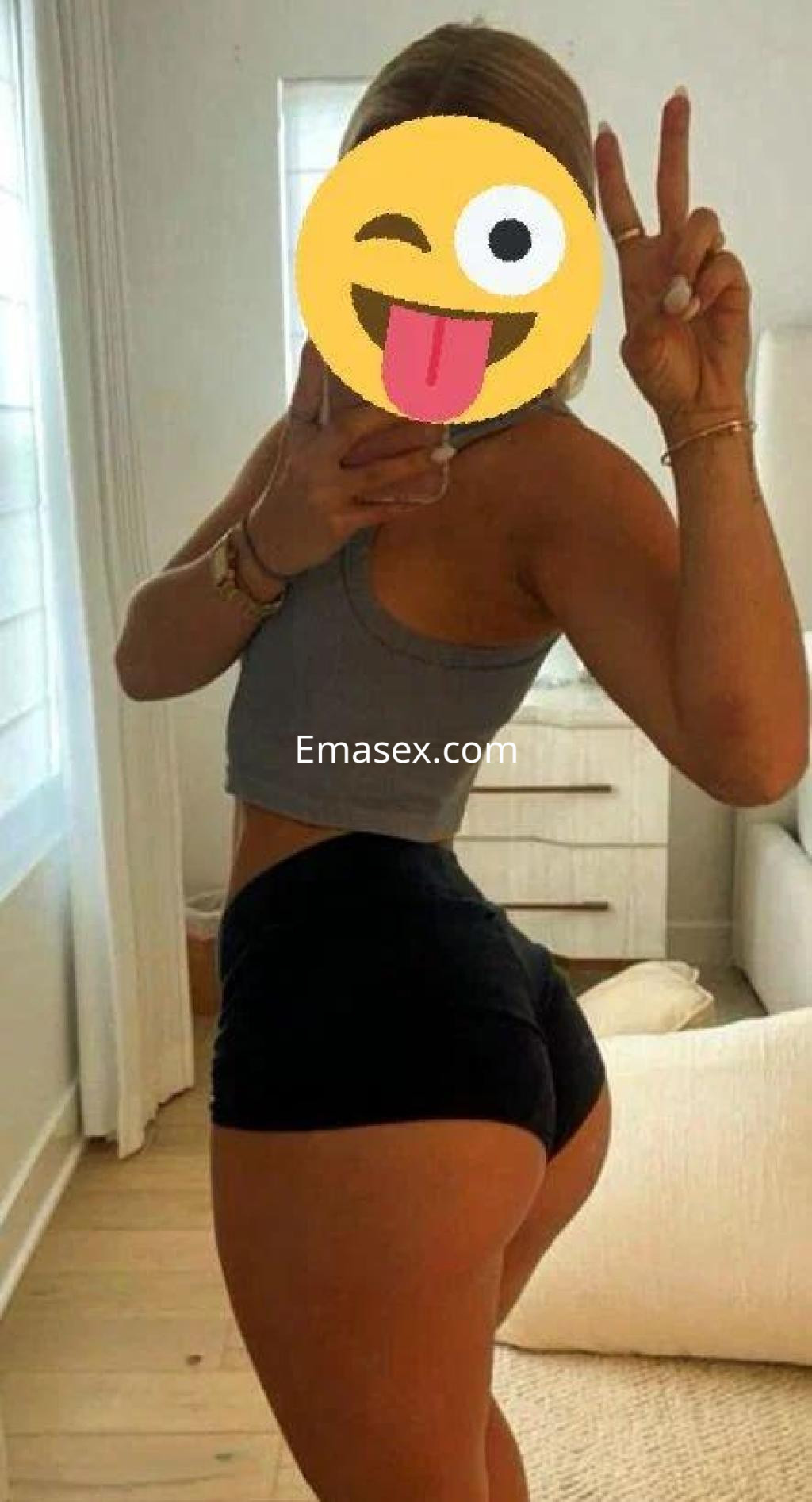 Puta en Córdoba posa de lado con top gris y pantalones cortos negros, mostrando una actitud desenfadada.