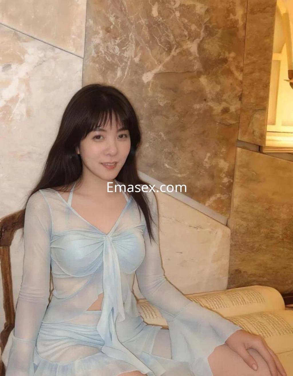 Puta en Coruña, vistiendo un conjunto ligero y transparente de color azul claro, sentada en un ambiente elegante.