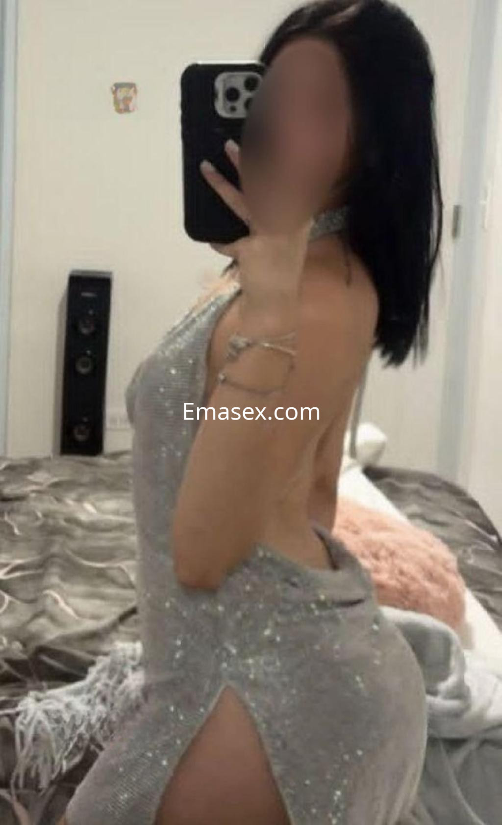 Escort en Valladolid posando de perfil con un vestido plateado brillante que tiene una abertura lateral.