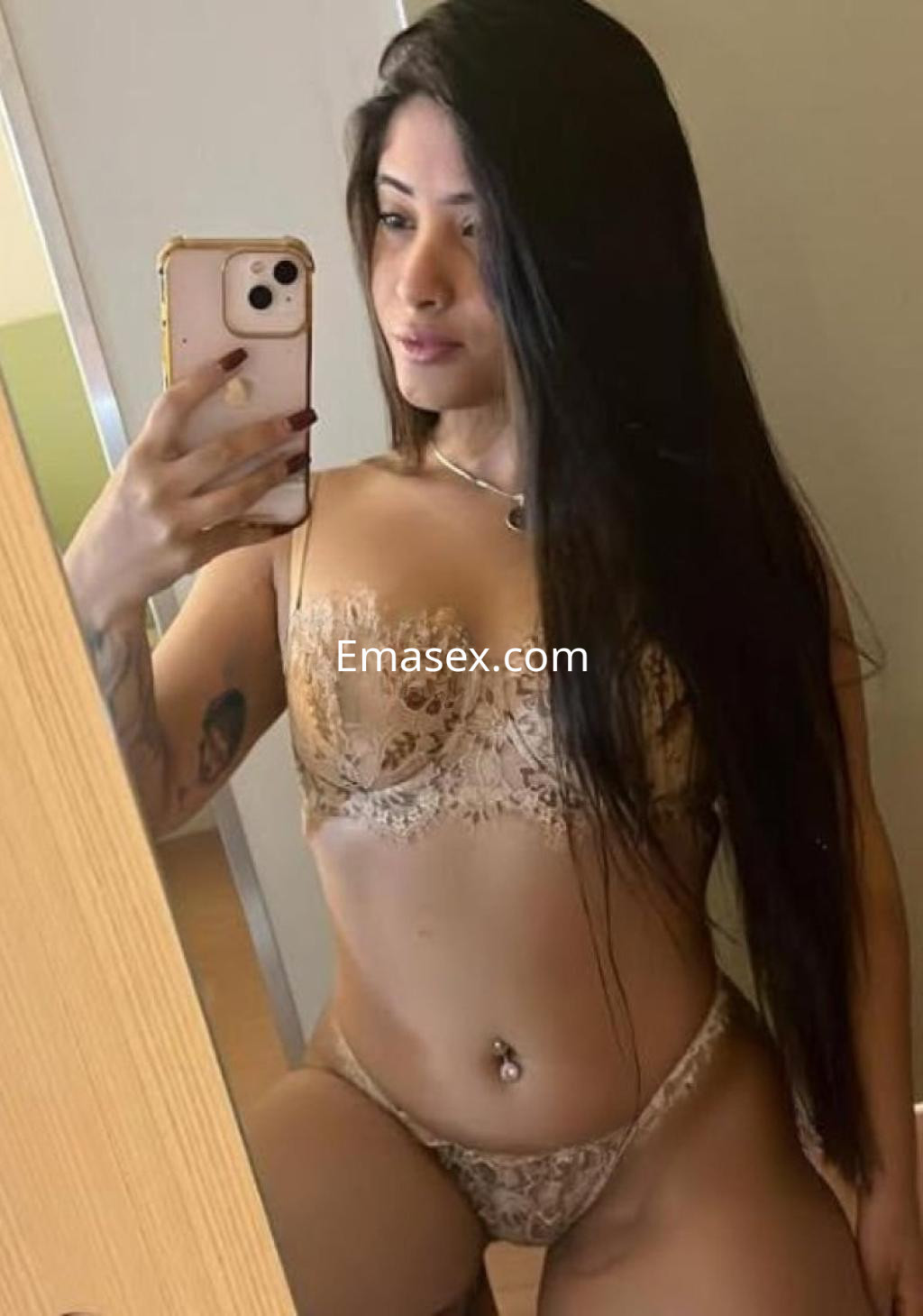 Puta en Almería posando frente al espejo con lencería dorada y cabello largo, luciendo una figura esbelta.