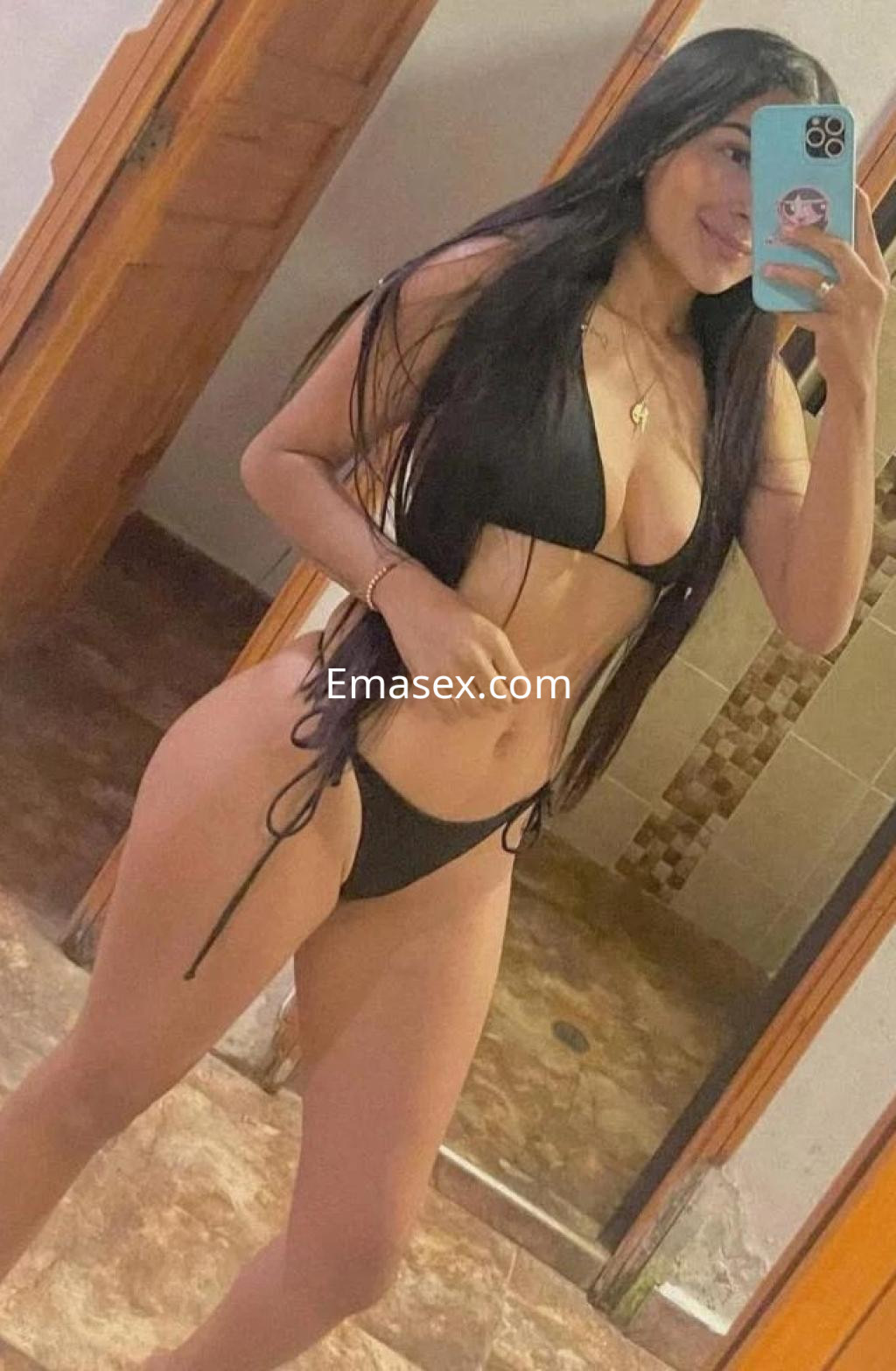 Puta en Granada posa con un bikini negro, mostrando su figura en un espejo con fondo de habitación.