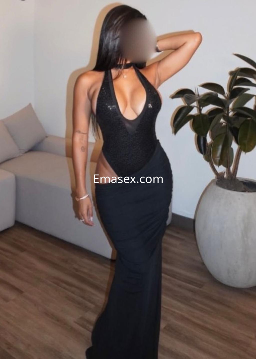 La puta luce un vestido largo negro con un escote pronunciado, en un ambiente moderno de Castellón.