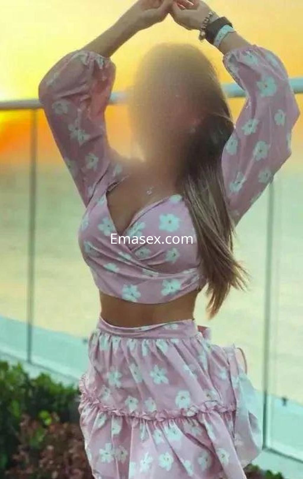 La puta lleva un vestido rosa con estampado de flores y posa al atardecer en Córdoba.