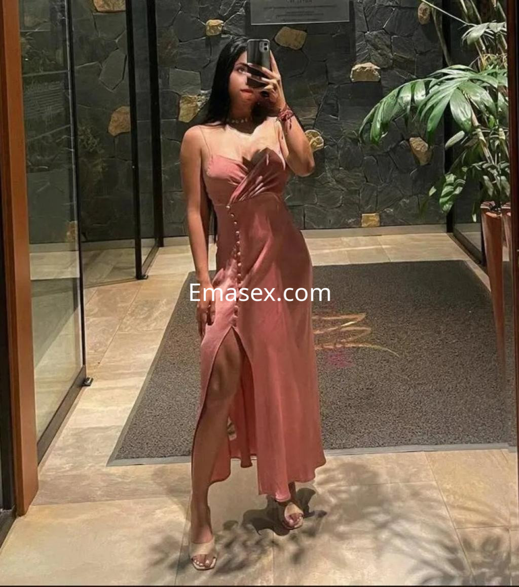 La puta viste un vestido largo de color rosa con abertura lateral, en un elegante vestíbulo en Barcelona.
