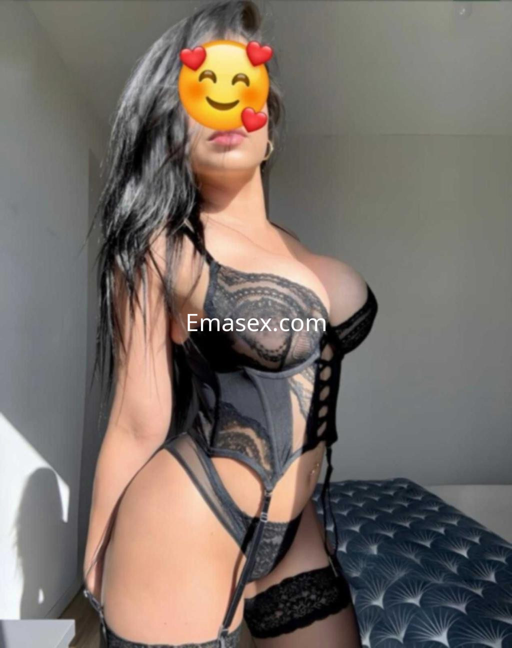 Escort en Badajoz viste un conjunto de lencería negra con detalles en encaje, posando con una expresión coqueta.