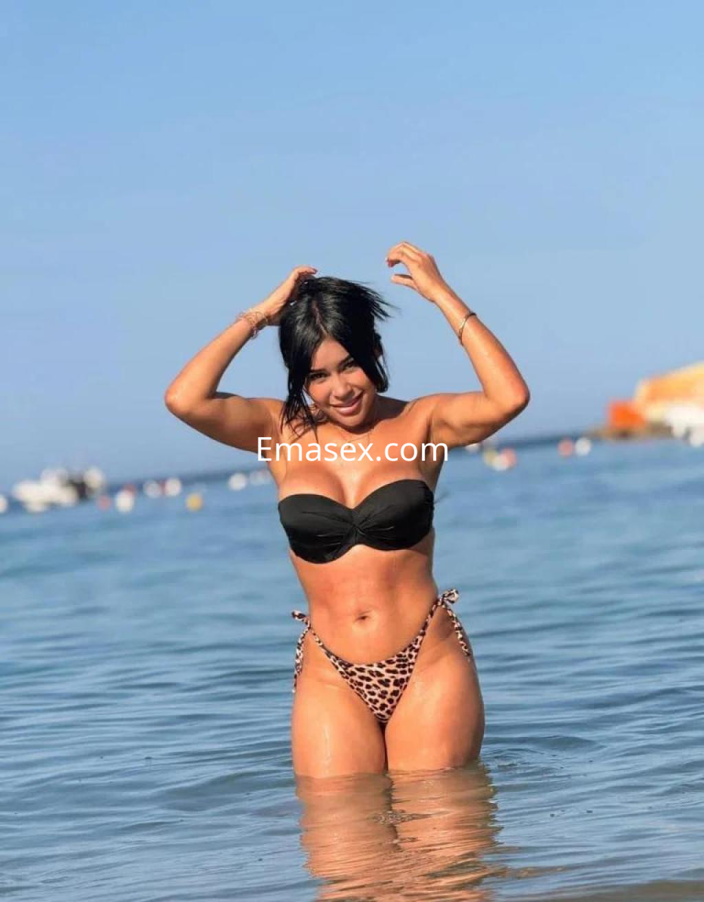 La puta luce un bikini negro con estampado de leopardo, disfrutando del agua en una playa de Barcelona.
