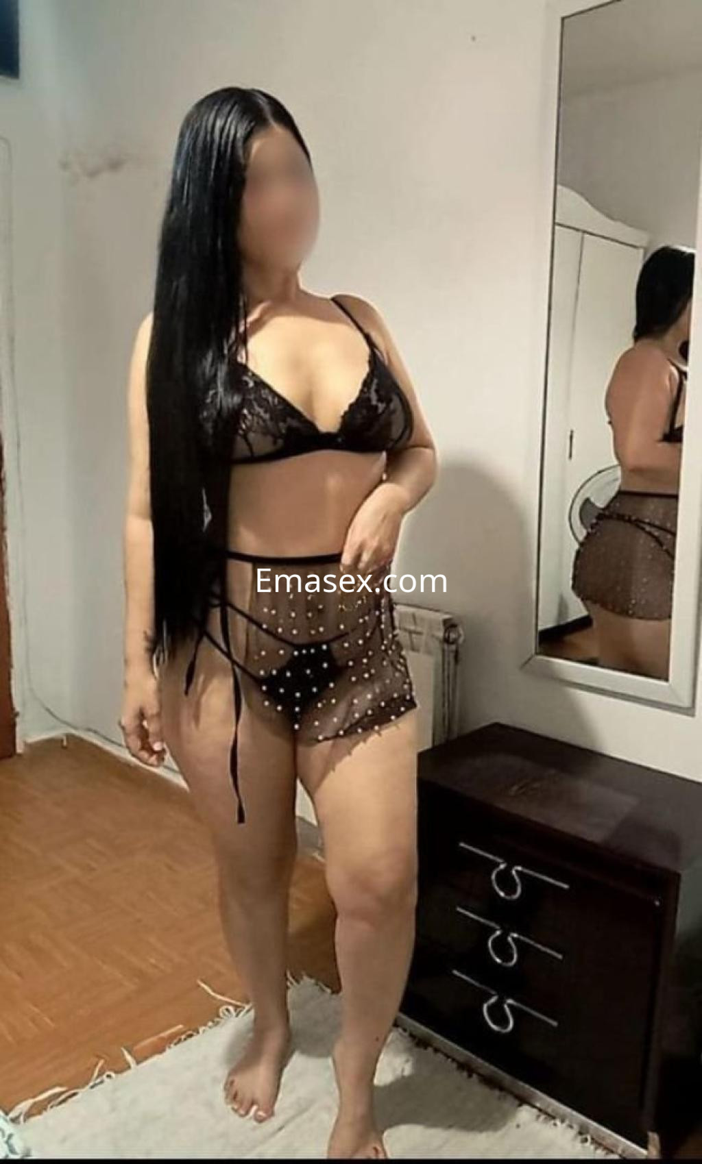 Escort de cabello largo y lacio, luciendo lencería negra con puntos blancos, en un ambiente interior en Cáceres.