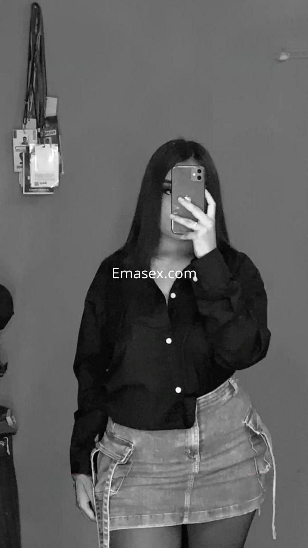 Puta en Córdoba, vestida con camisa negra y falda de mezclilla, posando frente a un espejo.