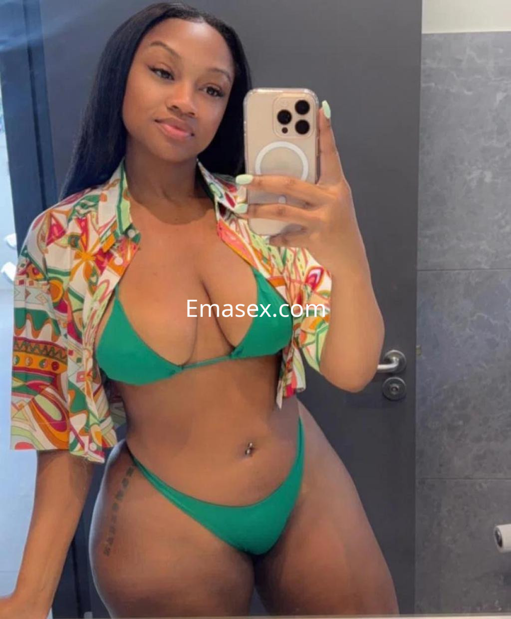 Escort en León con cabello largo y lacio, vistiendo un bikini verde y una camisa de estampado colorido.
