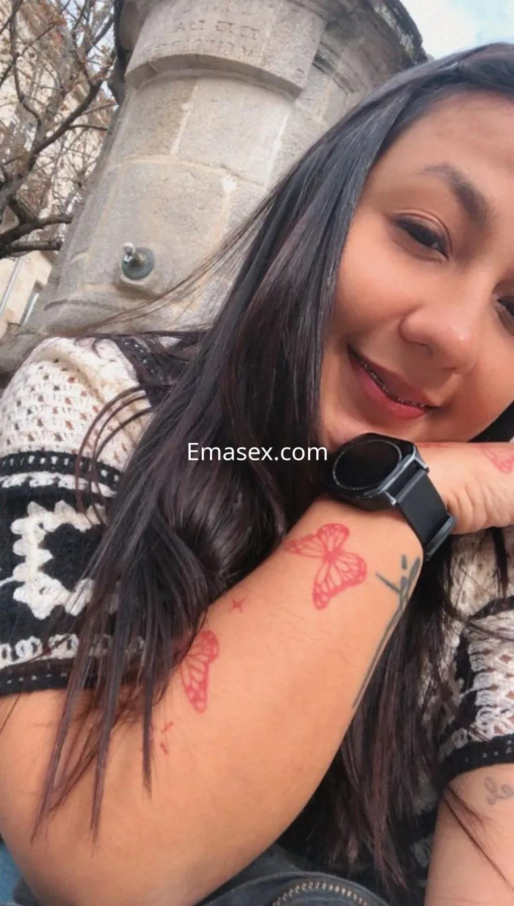 Puta con cabello largo y lacio, viste un suéter de punto, muestra tatuajes de mariposas en su brazo en Murcia.