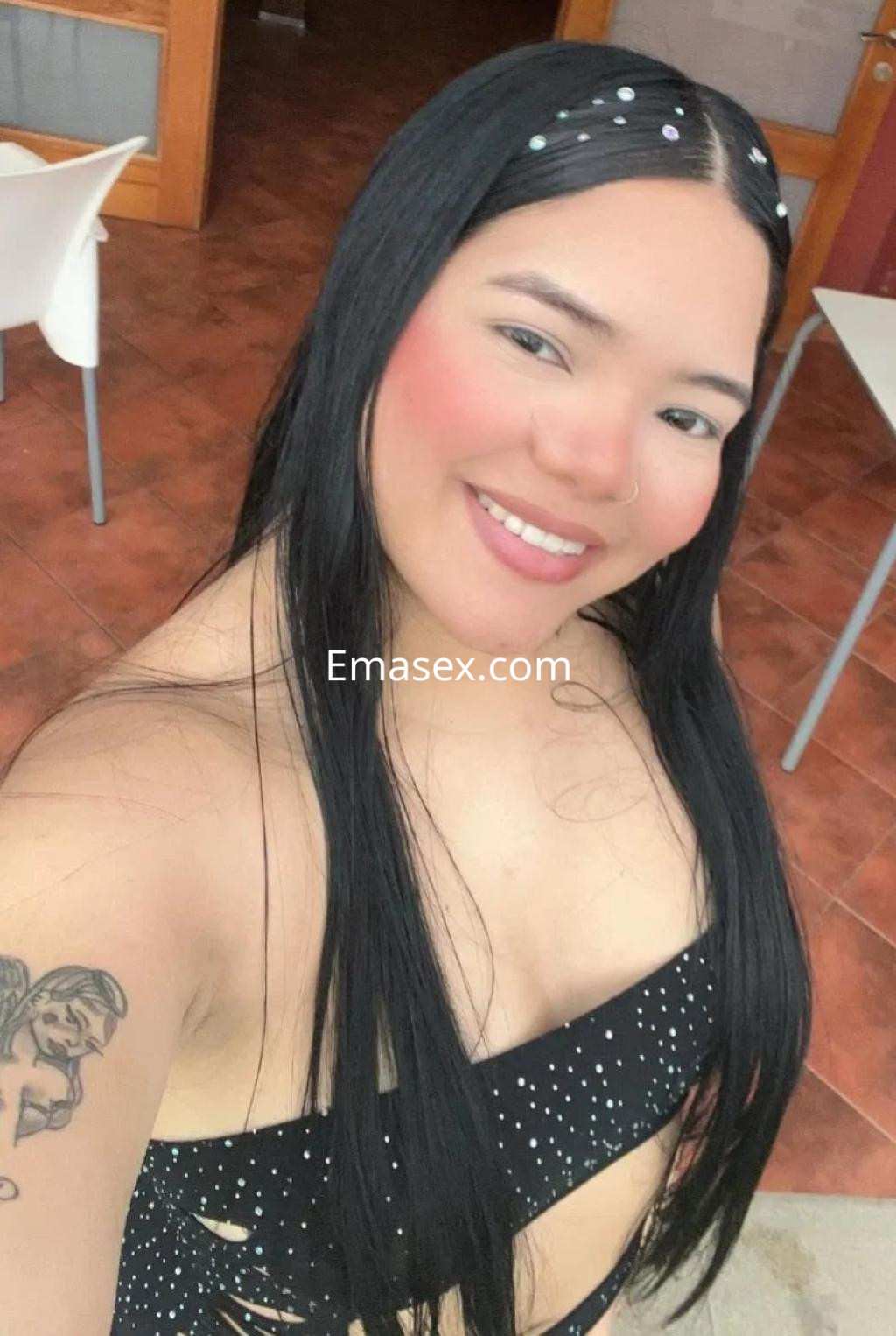 Escort en Granada sonríe mientras lleva un top negro con brillos y tiene el cabello largo y lacio.