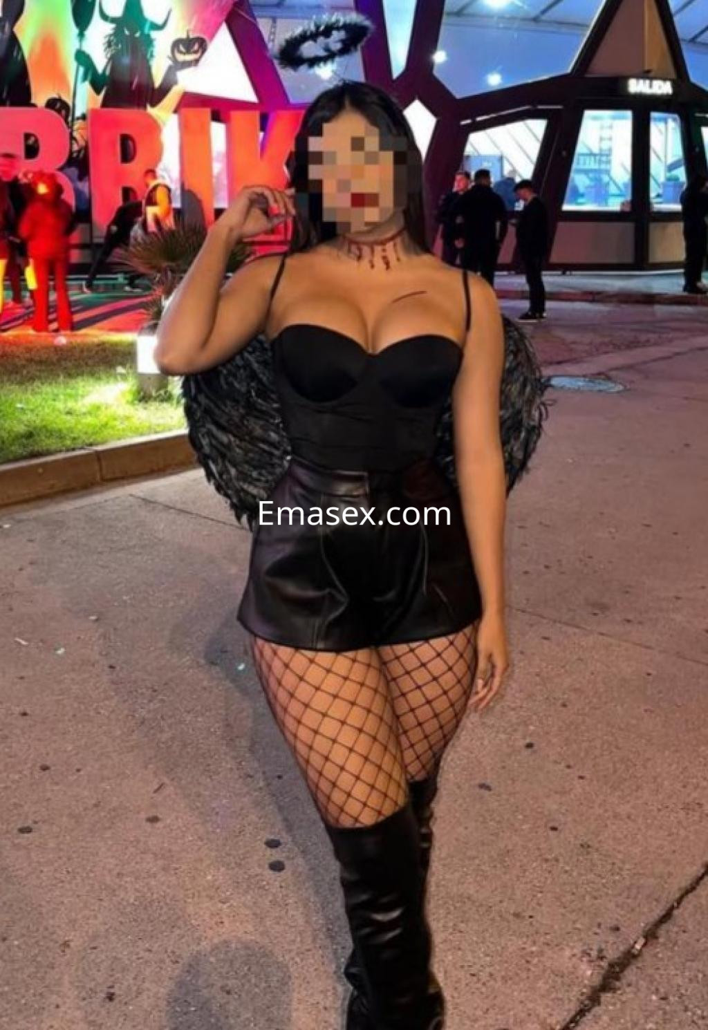 Escort en Tenerife con un atuendo negro, que incluye un top ajustado y falda corta de cuero, luciendo medias de red.
