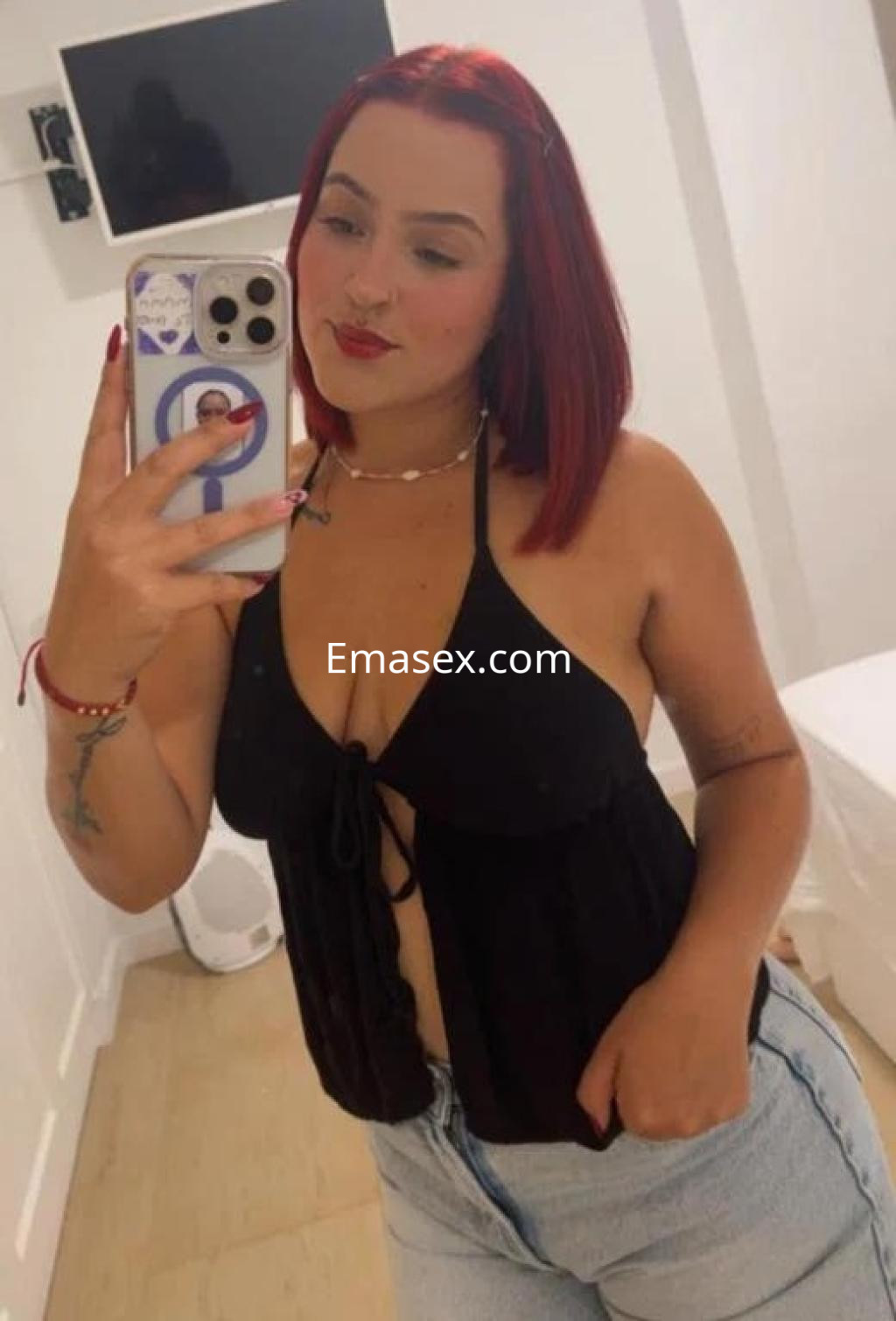 La puta posa con blusa negra y jeans en un ambiente de Tenerife, luciendo su cabello rojo.