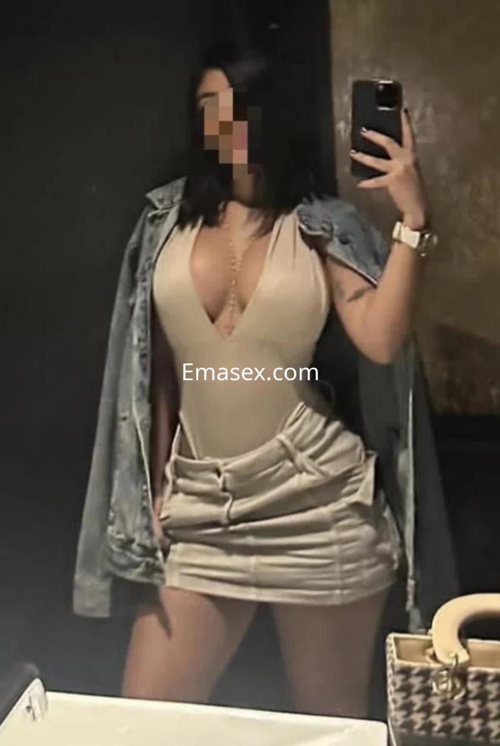 Escort en Las Palmas, posando frente al espejo con un vestido ajustado y chaqueta de mezclilla.