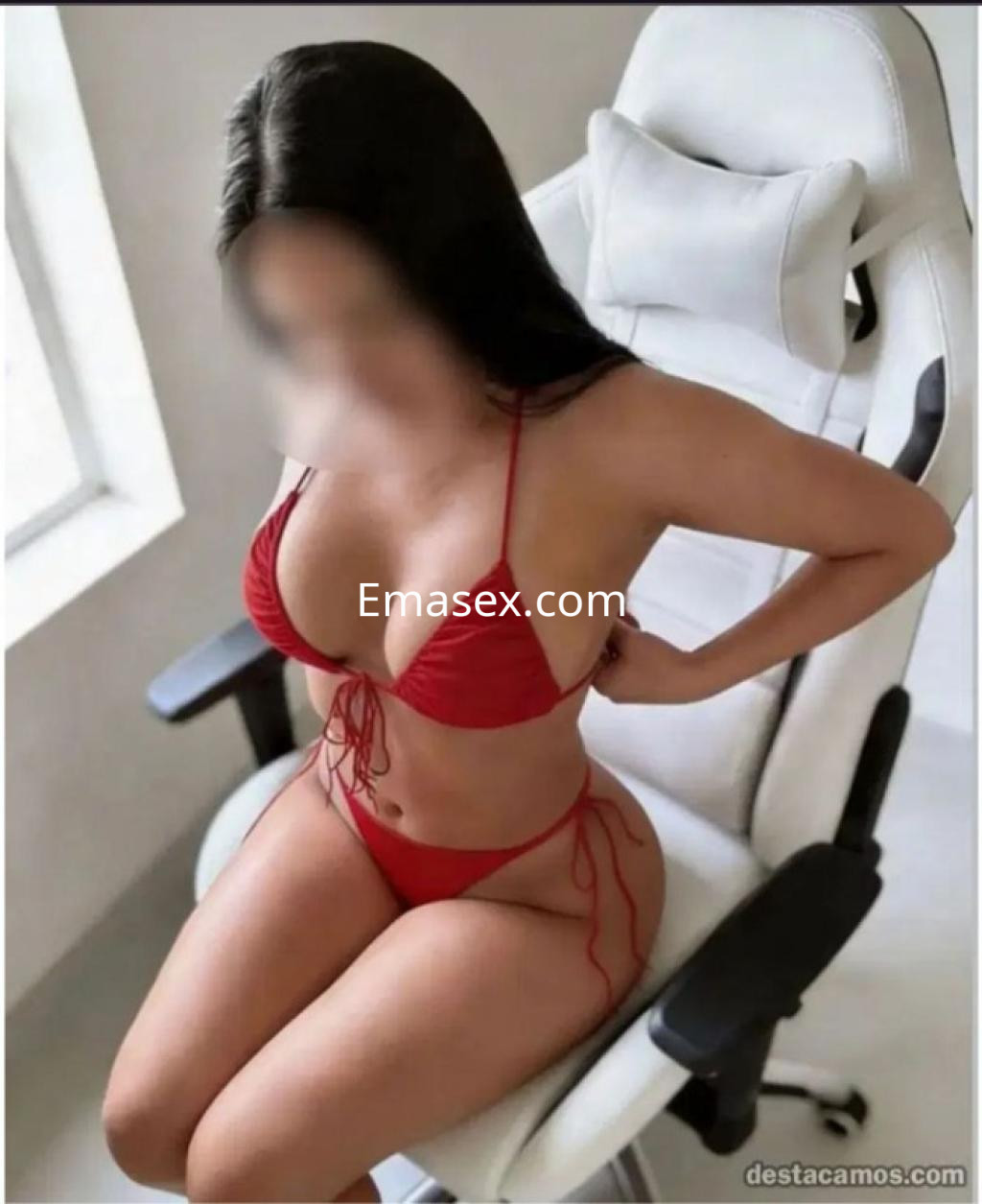 Puta en Zamora con un bikini rojo, sentada en una silla blanca, mostrando una pose seductora.
