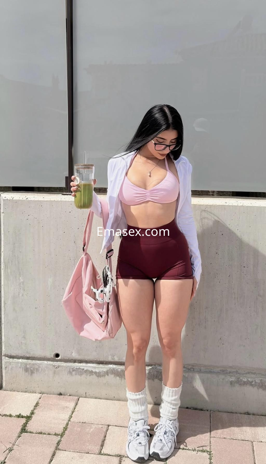 Puta en Pamplona viste un top rosa y shorts rojos, sosteniendo un vaso, con un look fresco y urbano.