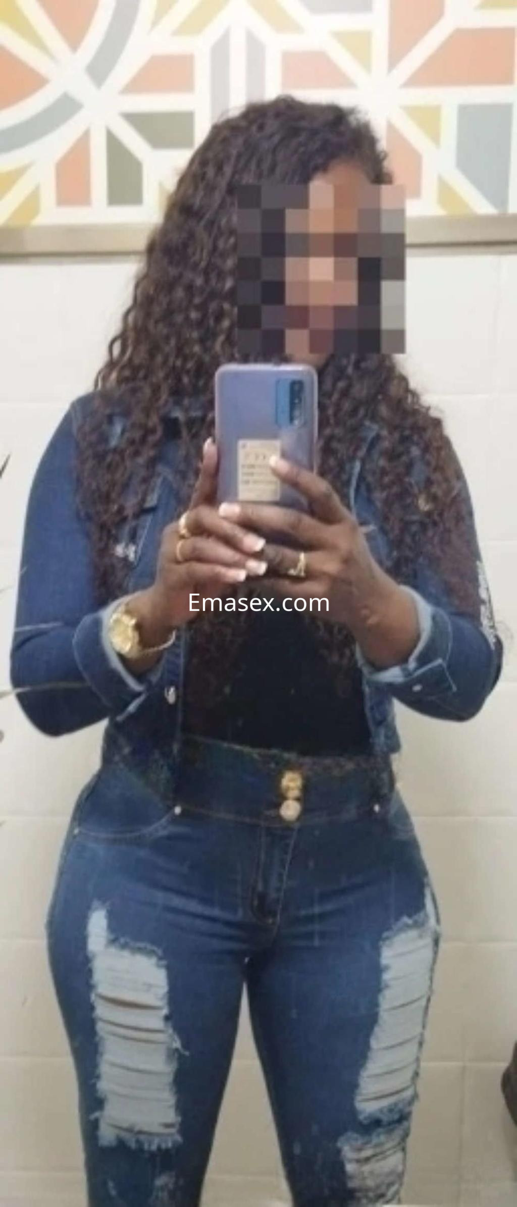 Puta en Albacete, con cabello rizado y oscuro, viste un conjunto de jeans ajustados y una chaqueta de mezclilla.