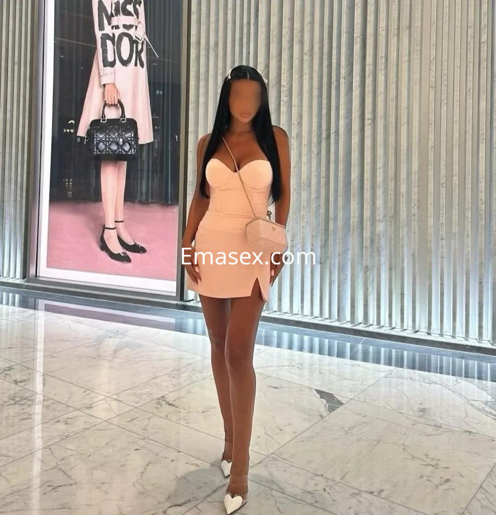 Escort en Alicante con vestido rosa ajustado y tacones altos, posando en un ambiente elegante y moderno.