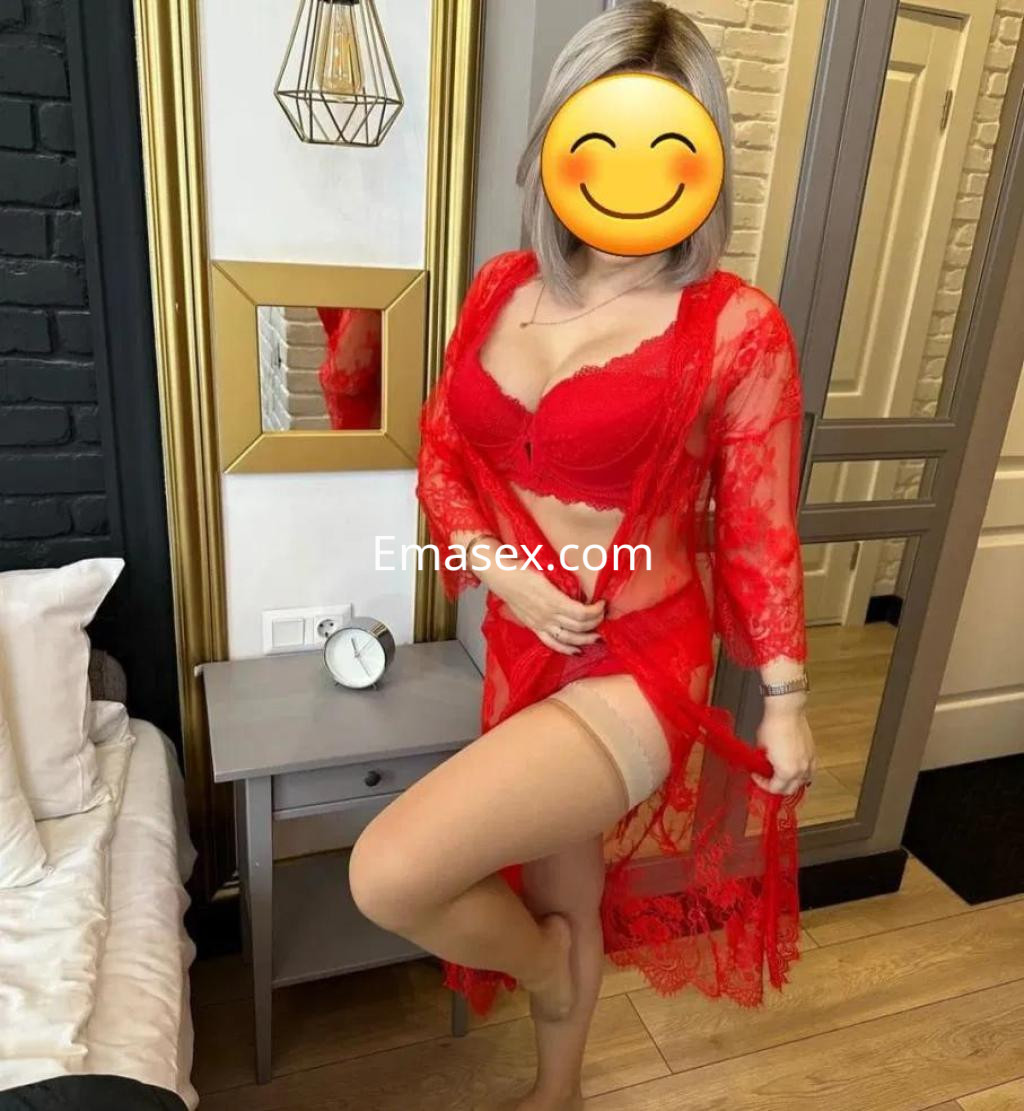 Escort en Badajoz, posando con un conjunto de lencería roja y una bata transparente, en un entorno elegante.