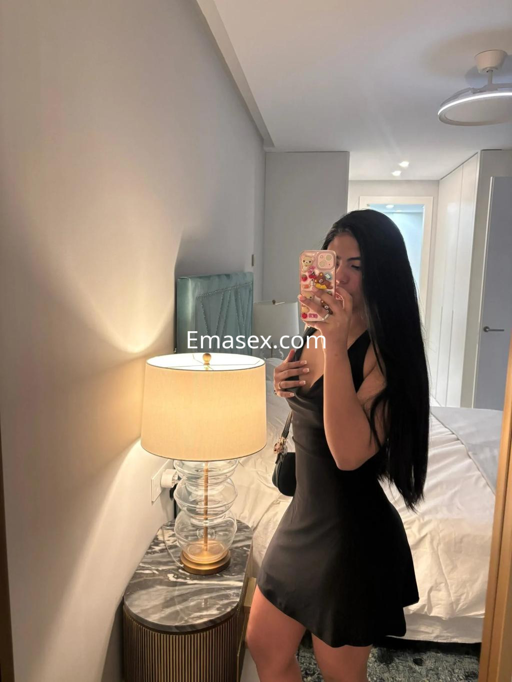 Puta con vestido negro ajustado y cabello largo posando frente a un espejo en una habitación de Burgos.