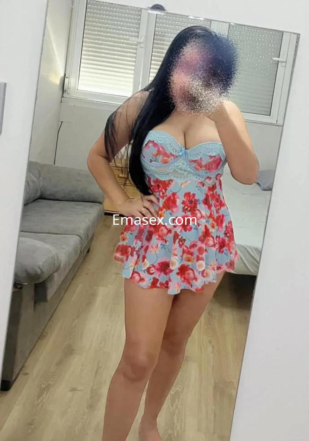 Escort en Burgos, luciendo un vestido corto con estampado floral y tirantes, en un ambiente interior.