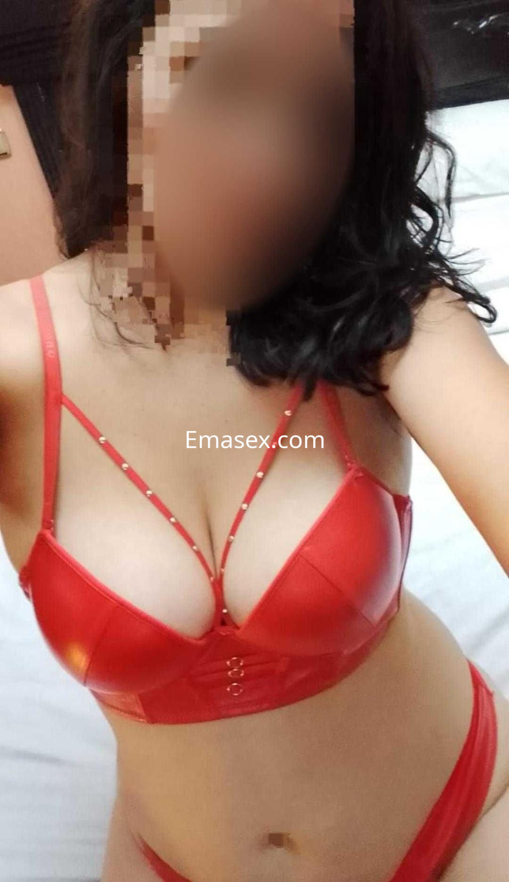 La puta viste un conjunto de lencería roja con detalles brillantes, posando en una habitación de Córdoba.