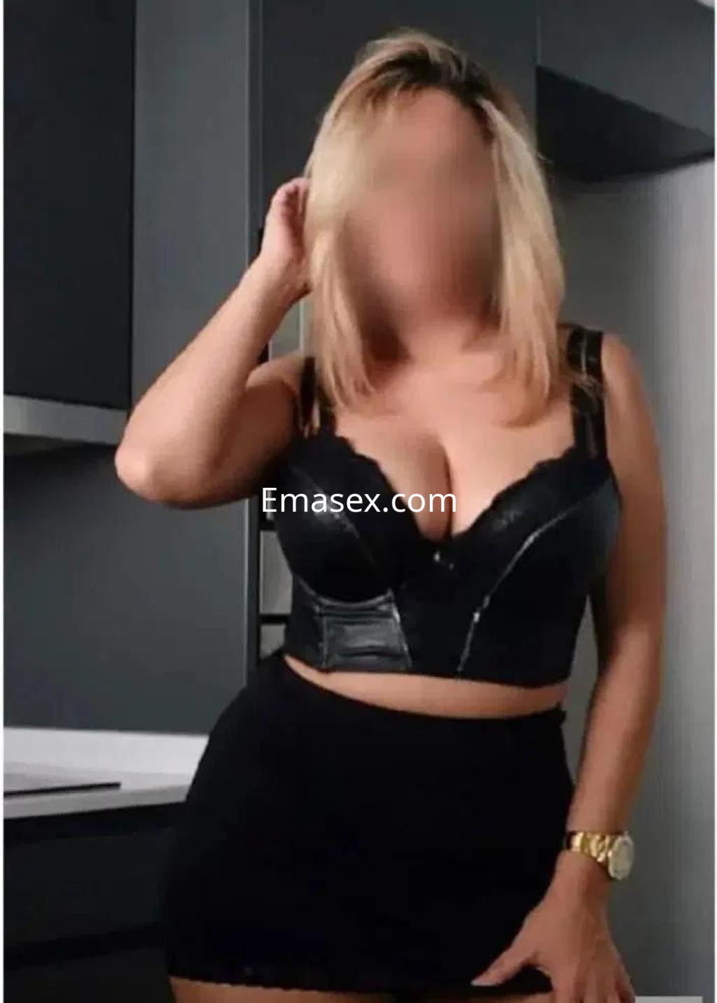 Puta de cabello rubio y lacio, viste un top negro ajustado y una falda corta en una cocina moderna de Granada.