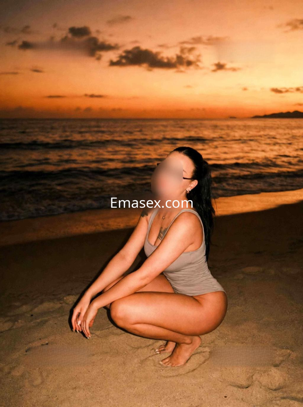 Puta en traje de baño claro, posando de rodillas en la arena de la playa al atardecer en Murcia.