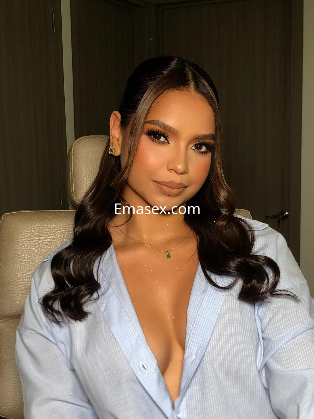 Escort en Murcia con cabello castaño oscuro y ondulado, vistiendo una blusa clara y luciendo un maquillaje elegante.