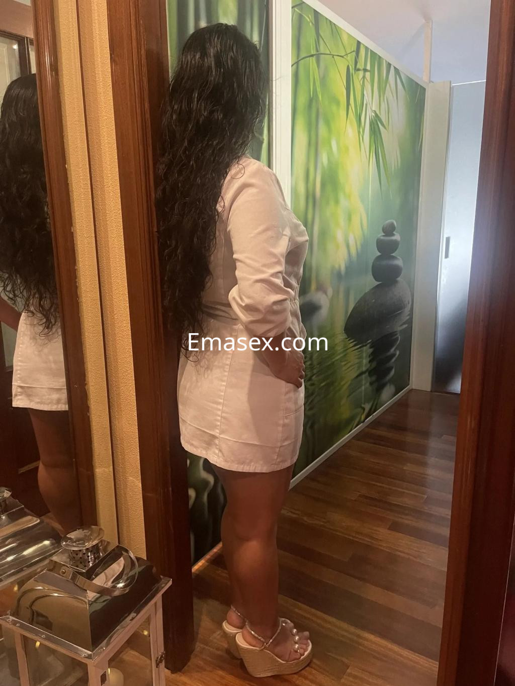 Escort en Vigo con cabello largo y suelto, vistiendo una blusa blanca y shorts, en un ambiente tranquilo.