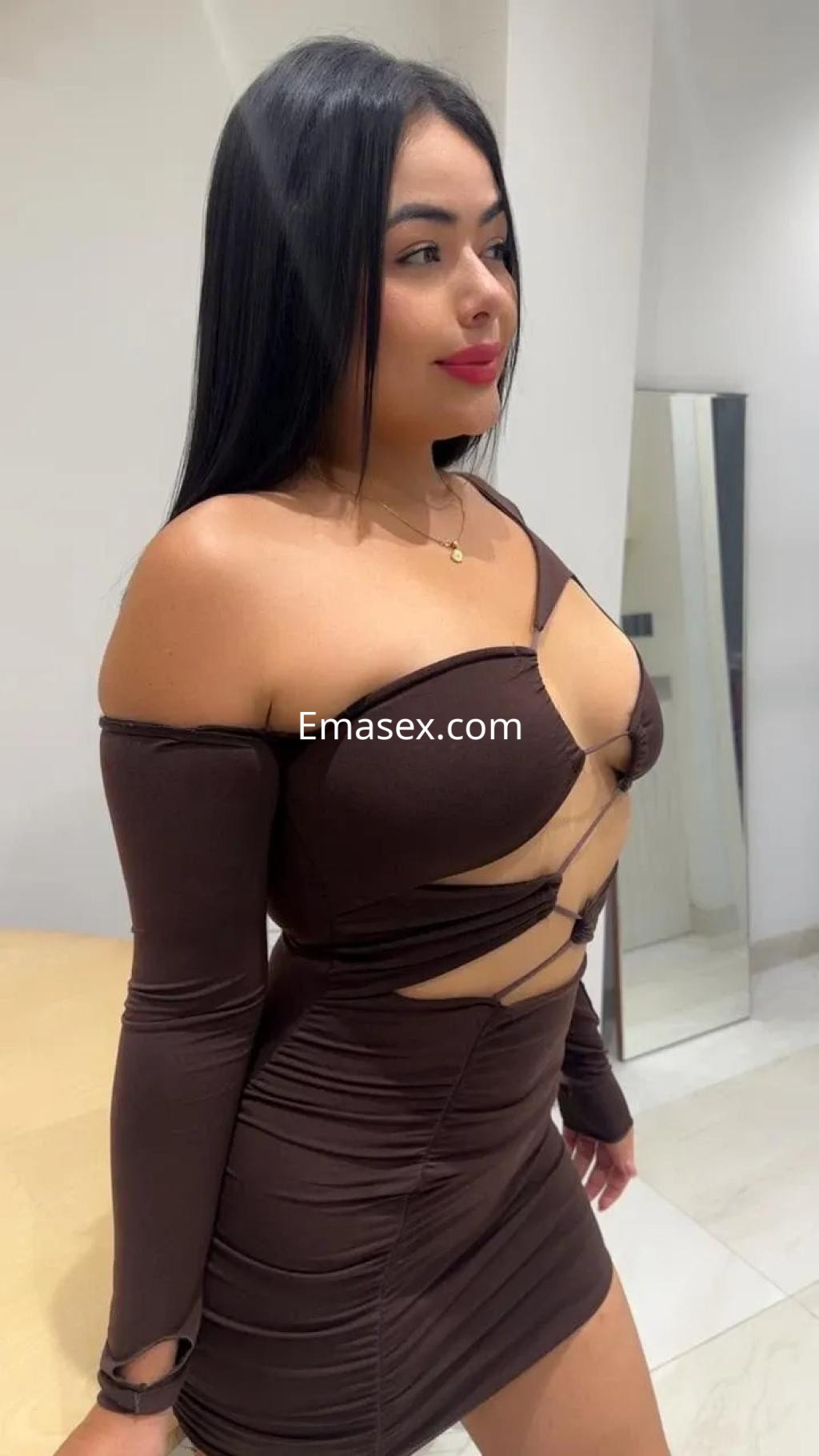 Escort en Sevilla con un vestido marrón ajustado y detalles recortados, posando con una expresión segura.
