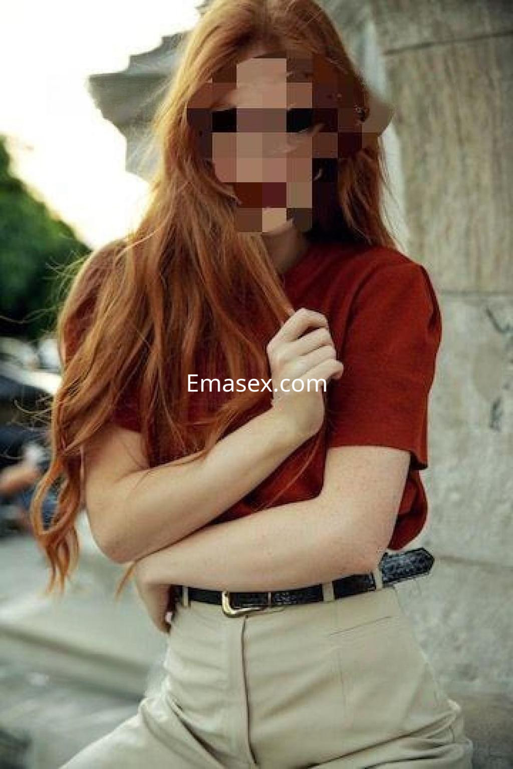 Puta de cabello largo y pelirrojo con blusa marrón y pantalones claros, posando en un entorno urbano en Zaragoza.