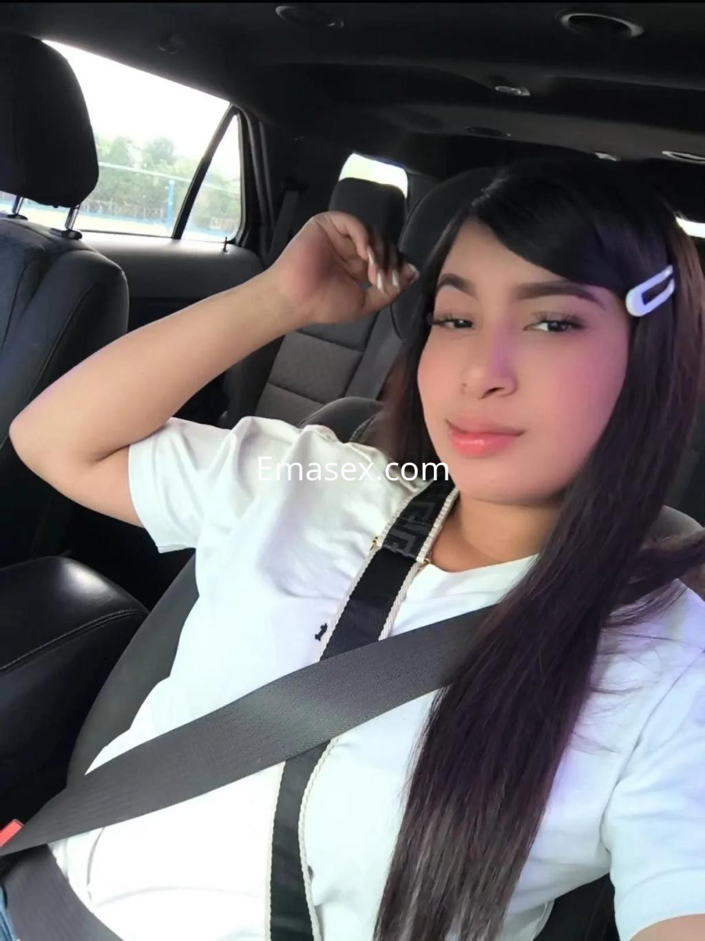 La puta posa en el interior de un coche, luciendo una camiseta blanca y con el cabello largo y lacio en Zaragoza.