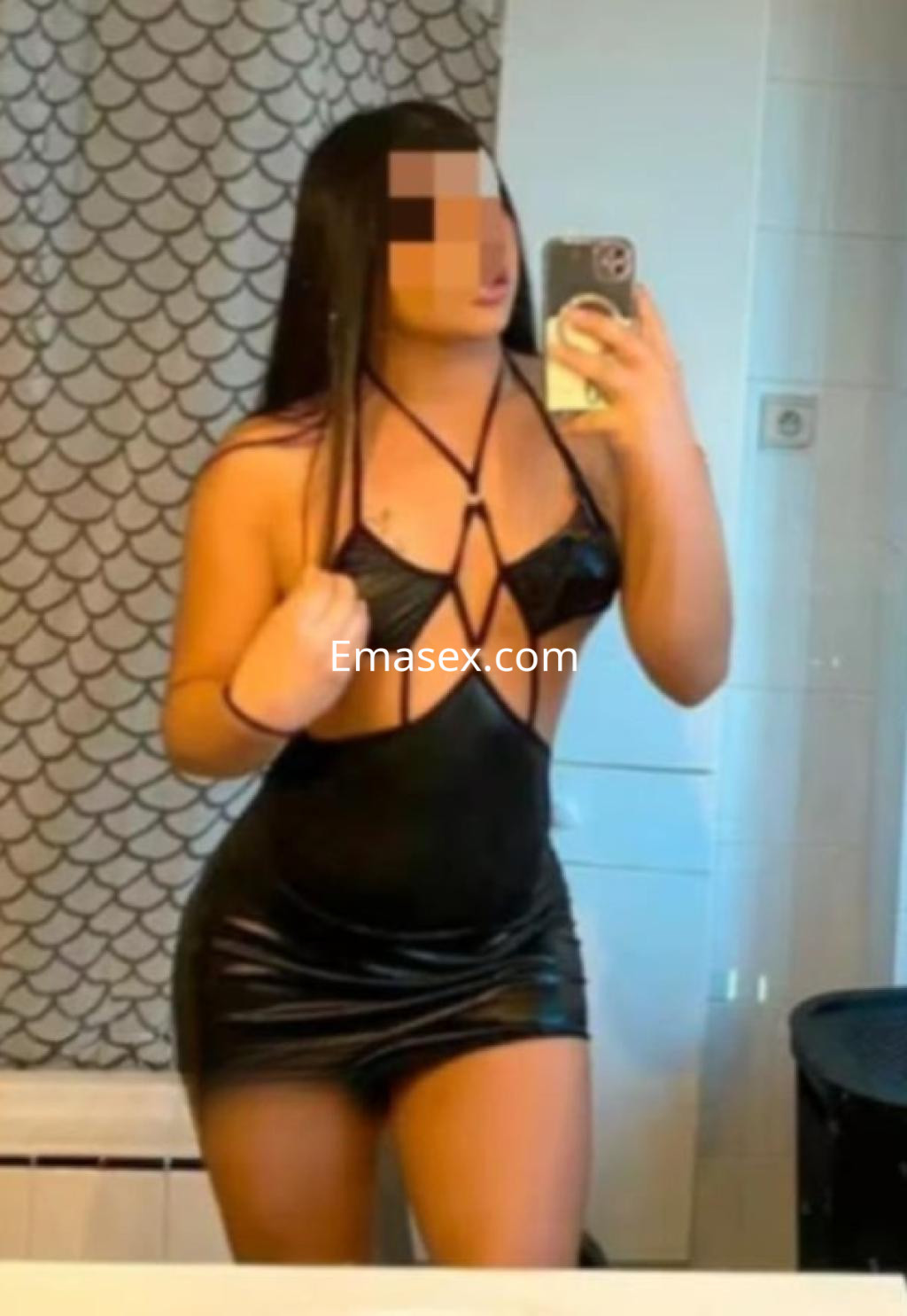 Escort en Granada luciendo un vestido negro ajustado, posando frente a un espejo en un baño.