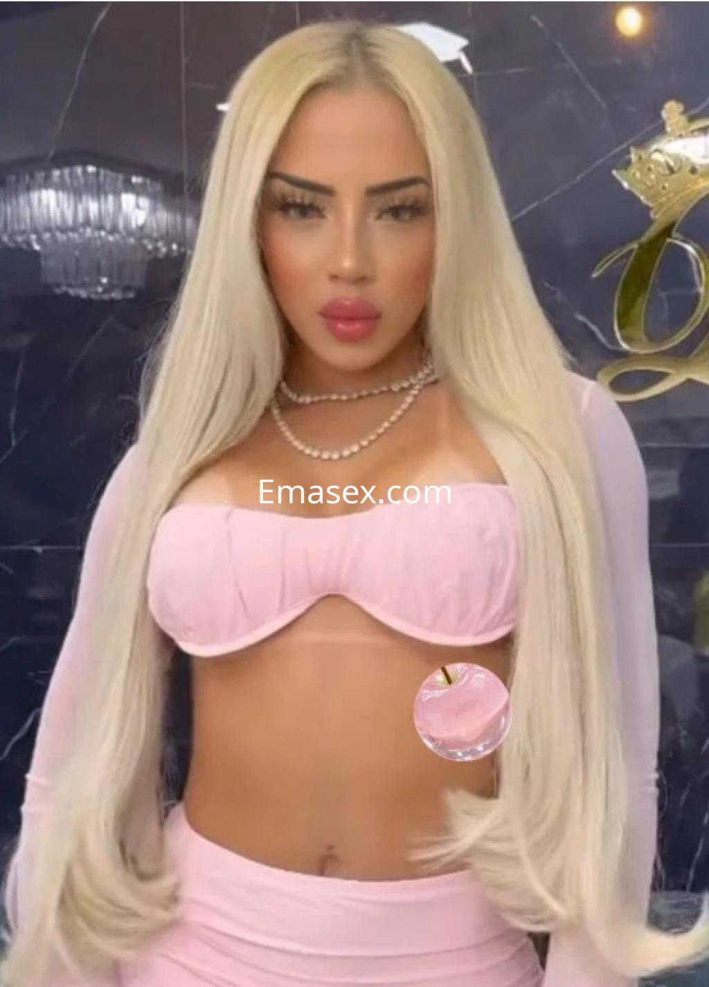 Escort en Sevilla con cabello largo y rubio, usando un top rosa y una falda a juego, posando con elegancia.