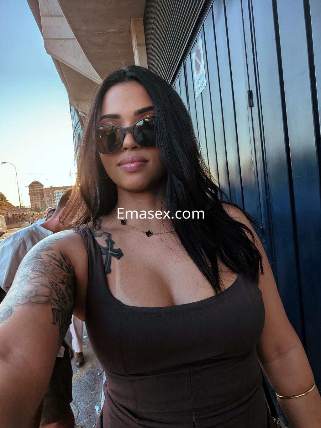 Puta en Pamplona, con cabello largo y lacio, usando un vestido marrón y gafas de sol, posando con confianza.