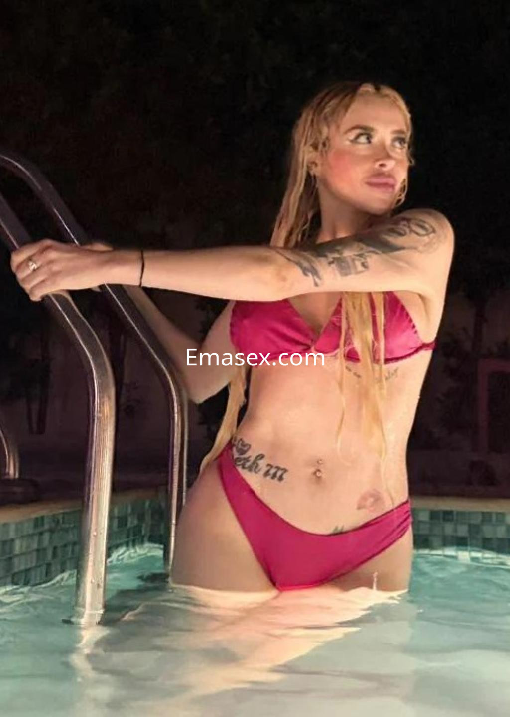 Puta en Las Palmas, luciendo un bikini rosa mientras se apoya en la escalera de una piscina nocturna.