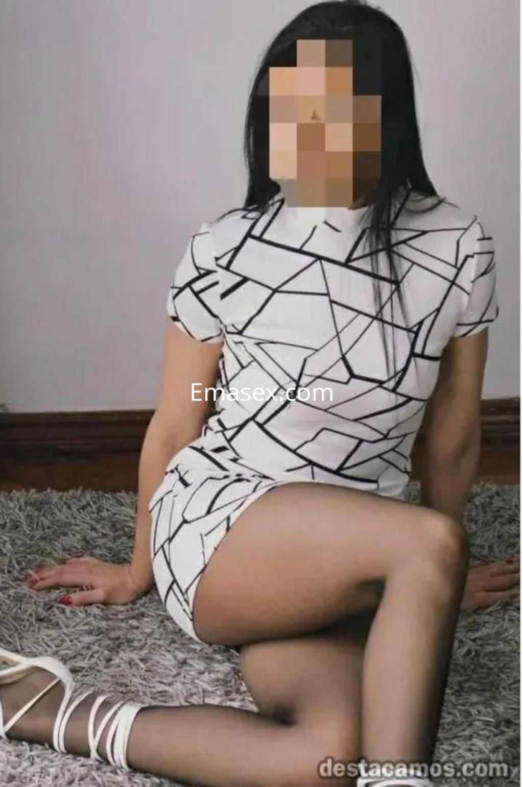 Puta posando en Alicante con vestido corto de patrones geométricos y tacones, sobre una alfombra gris.