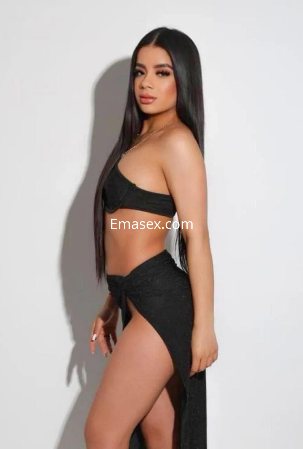 Puta en Palma de Mallorca, posa de perfil con un top negro y una falda larga, mostrando su figura esbelta.