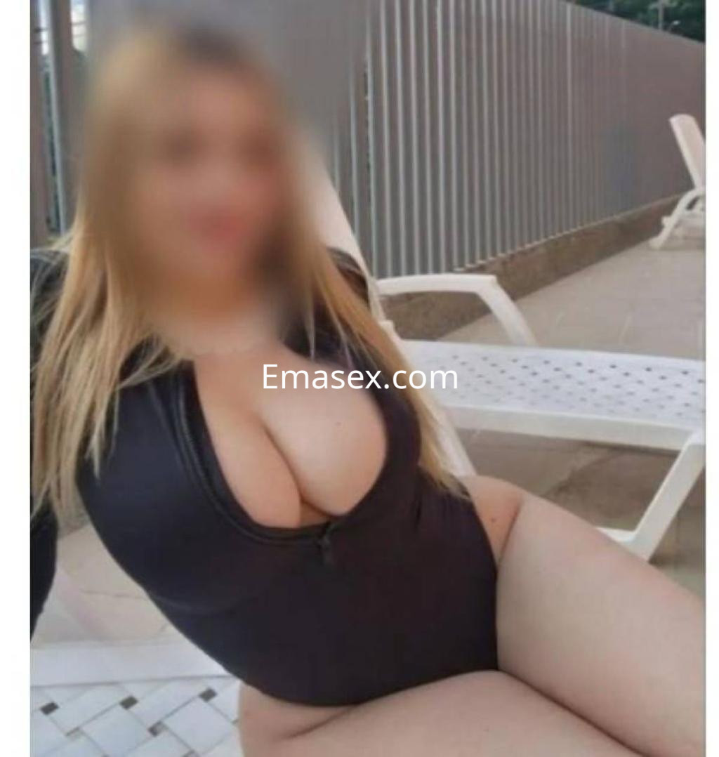 Puta en Cádiz, posando con traje de baño negro, sentada en una tumbona, mostrando sus curvas.