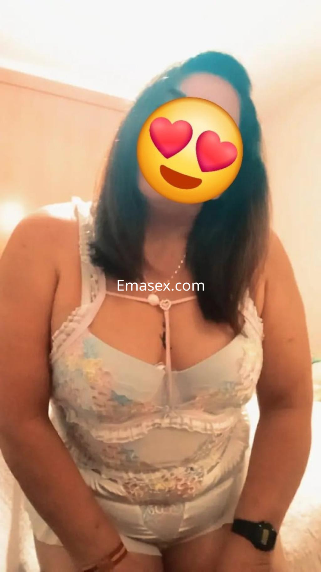 Escort en Granada, con cabello castaño y lencería clara, posando en un ambiente acogedor.