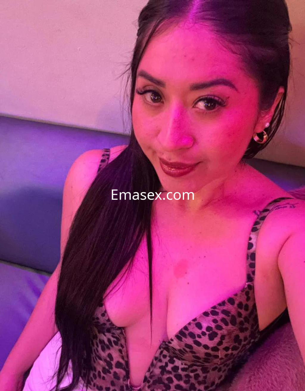 Escort en Sevilla con cabello largo y oscuro, vistiendo un sujetador de leopardo en un entorno con luz tenue.