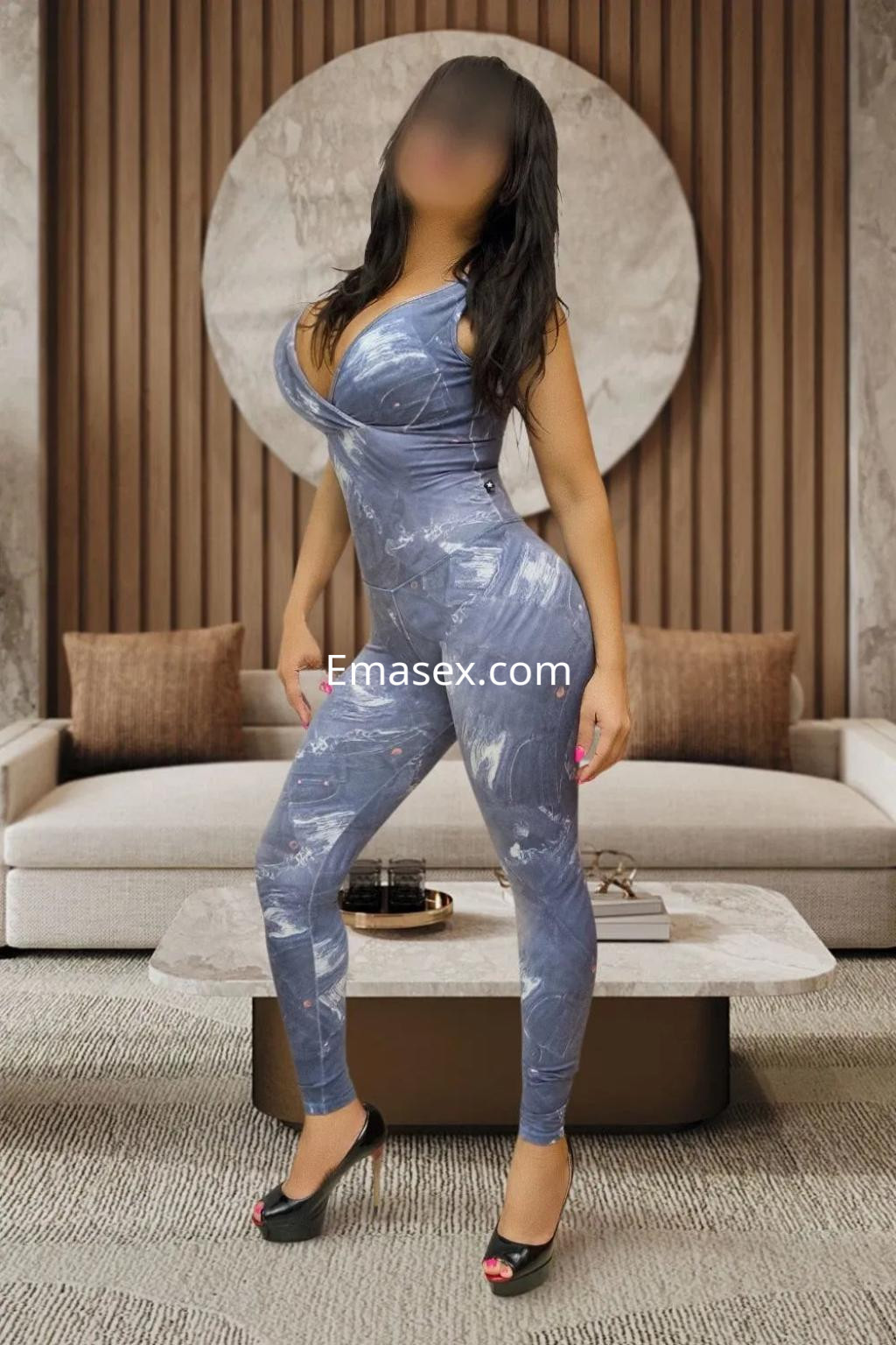Puta en Valencia luciendo un ajustado mono azul con estampado, posando en un elegante salón.