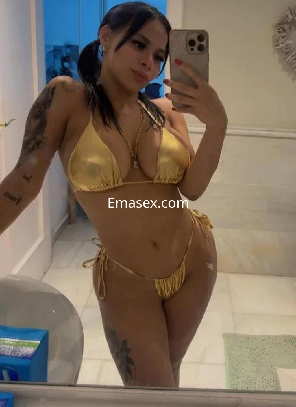 Puta posando en un baño con un bikini amarillo, luciendo su cabello oscuro y tatuajes en los brazos, en Málaga.