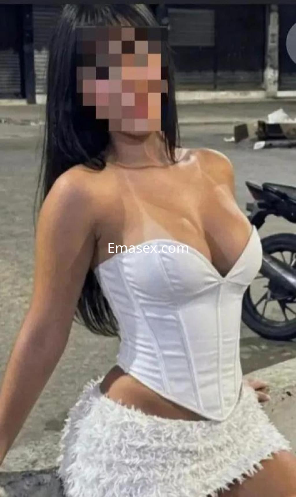 Puta en Castellón, luciendo un corset blanco y una falda corta, con cabello largo y lacio en un ambiente urbano.