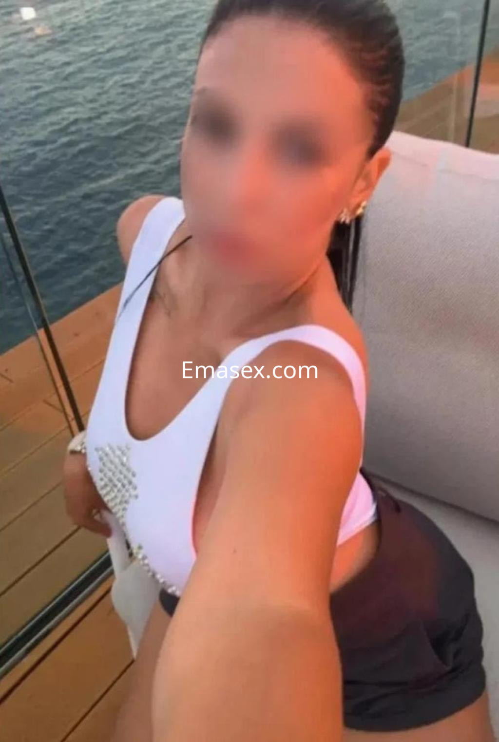 Puta posando con un traje de baño blanco en un entorno junto al mar en Tenerife, luciendo un peinado recogido.